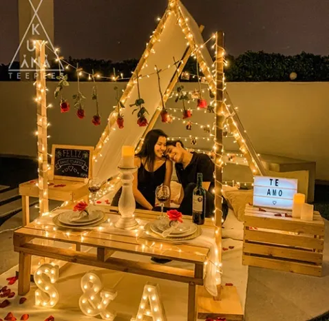 Paquete romántico completo con varios elementos incluyendo luces, velitas, fotos, iniciales, vino, pizarra, pétalos y rosas
